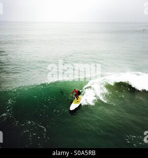 Un stand up surfer che naviga in un'onda. Manhattan Beach, California USA. Foto Stock