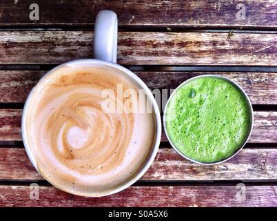 Tazza di cappuccino e bicchiere di succo verde sulla tavola in legno rustico Foto Stock