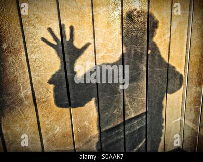 Un uomo getta un' ombra sul muro, contando sulla sua mano. Numero cinque. Foto Stock