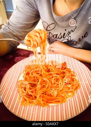 Donna di mangiare gli spaghetti con sugo di pomodoro Foto Stock