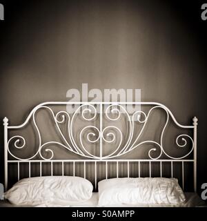 Ghisa bianca la testa del letto e cuscini bianchi, cross-process tonico parete marrone Foto Stock