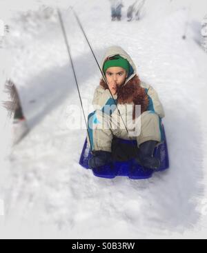 Il ragazzo corse in slittino nella neve Foto Stock