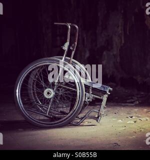 Lugubre la sedia a rotelle in edificio abbandonato Foto Stock
