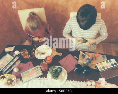 Fratello e Sorella di pittura delle uova di Pasqua in casa Foto Stock