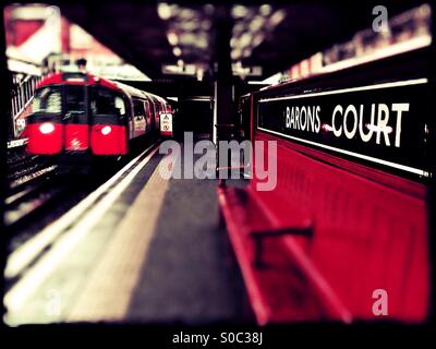 In direzione ovest la linea di Piccadilly treno arrivando a Barons Court stazione della metropolitana di West London, England, Regno Unito, Europa Foto Stock