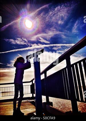 Giovane ragazza in silhouette con telescopio al fine di pier Foto Stock