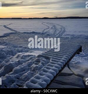 La casa con pista di pattinaggio su ghiaccio, un molo e piste da sci al tramonto in un idilliaco Arctic lago ghiacciato in inverno in Scandinavia Foto Stock