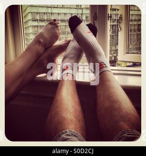 Un giovane appoggiando i piedi su un hotel davanzale in un hotel dopo una dura giornata di camminare su una romantica pausa in città a Copenhagen Foto Stock