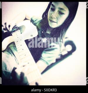 Di undici anni ragazza suona la chitarra elettrica. Foto Stock