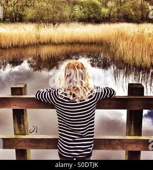 Ragazza giovane cerca su stagno a Yarrow Valley vicino a Chorley in Lancashire Foto Stock