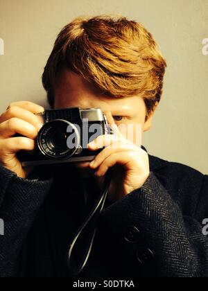 Dai capelli rossi boy scattare fotografie con una Olympus Pen semitelaio telecamera cinematografica Foto Stock