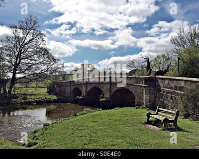 Il ponte di pietra sul fiume collettore nel villaggio di Ilam, Staffordshire Foto Stock