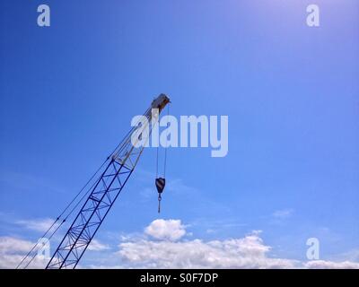 Una gru mobile contro uno sfondo di cielo blu e nuvole drammatico Foto Stock