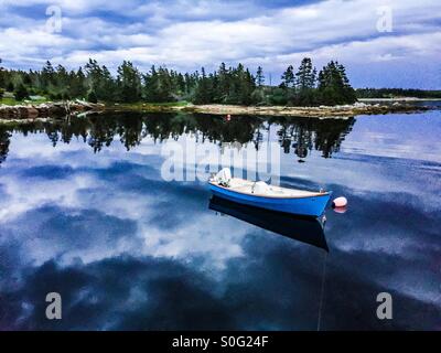 Birra Storm. Una barca all'ancora come le nuvole pesanti si raccolgono, riflesse in acque ancora calme, Halifax, Nova Scotia, Canada. Foto Stock