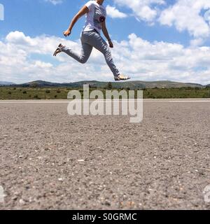 Donna salta con nessun capo sull'immagine su una strada vuota Foto Stock