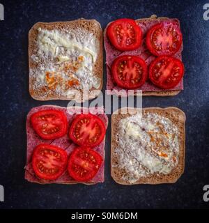 Tutti square. Due panini pane quadrato essendo preparata con pomodori, corned beef e salamoia. Foto Stock