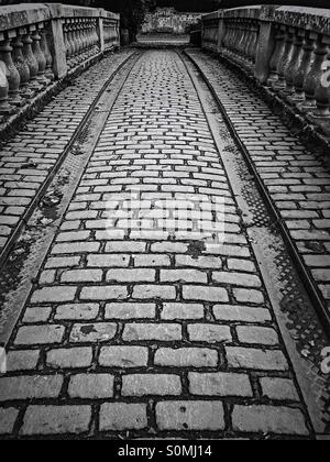 Strada acciottolata sopra il ponte storico e i binari delle carrozze, Pollok Park, Glasgow, Scozia, Regno Unito Foto Stock