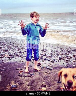 Ragazzo su una spiaggia essendo photobombed dal cane. Foto Stock