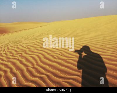 Ombra di un fotografo di scattare le foto nel deserto Dubai EMIRATI ARABI UNITI Foto Stock