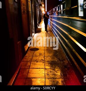 Giovane uomo che corre lungo una strada scura di notte Foto Stock