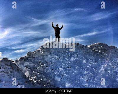 Un ragazzo di teen sulla sommità di un enorme cumulo di neve Foto Stock