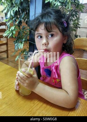 Bambina bere un succo di arancia. Foto Stock