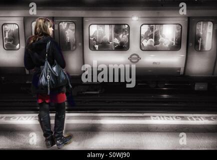 La donna in attesa del treno alla stazione di Barbican, Londra Foto Stock