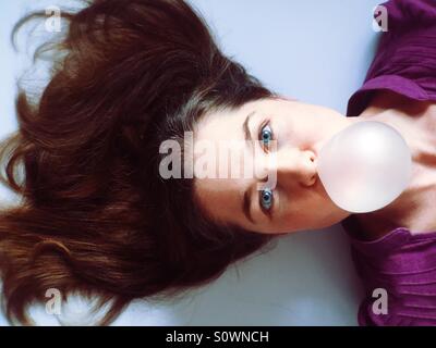 Donna soffiando una bolla bubble gum Foto Stock