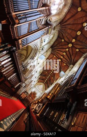 L'interno di una grande cattedrale ornato di sculture in legno e muratura decorativa. Guardando in giù il tappeto rosso sul corridoio di una grande chiesa in corrispondenza di un angolo di drammatico. Foto Stock