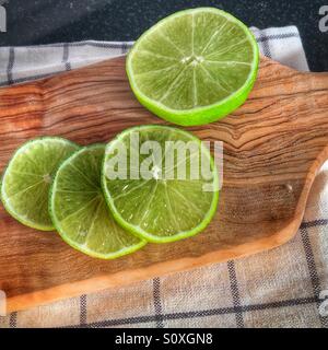 Fette di limes in appoggio su di un legno d'ulivo platter Foto Stock