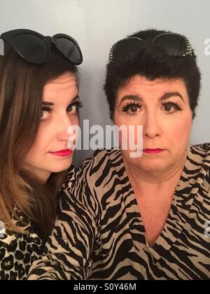 Una madre e figlia indossando leopard e fantasia zebra abbigliamento e occhiali da sole hanno sulle ciglia finte e rosa rossetto Foto Stock