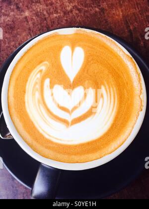 Caffè in tazza nera con cuore forme di schiuma sul caffè crema Foto Stock