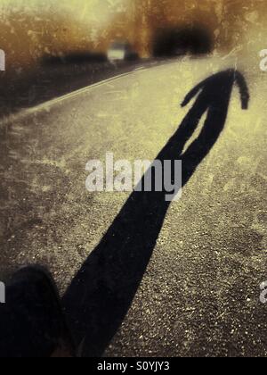 La lunga ombra di un uomo a camminare lungo una strada. Foto Stock