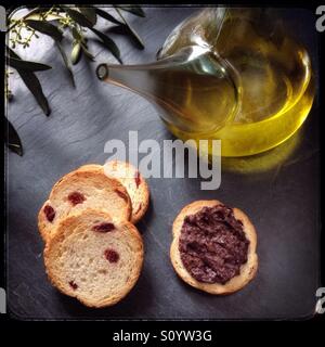 Home-cured black mature Empeltre spagnolo olive tapenade con ampolla di olio extra vergine di oliva e biscotti. Foto Stock