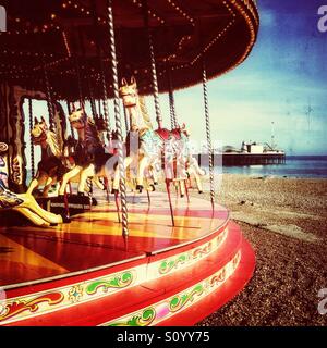 Il vecchio stile giostra sulla spiaggia di Brighton con pier in background Foto Stock