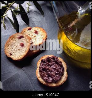 Nero-stagionati home-cured Empeltre spagnolo olive tapenade con una ampolla di olio extra vergine di oliva e biscotti. Foto Stock