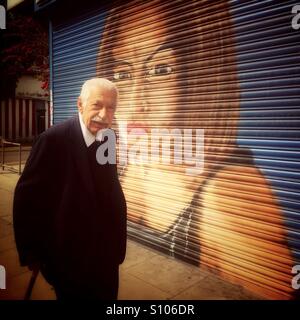 Vecchio Uomo cipriota in Harringay, Green Lanes. Passando dal negozio con un ritratto di una donna dipinta sul suo persiane. London, Regno Unito Foto Stock