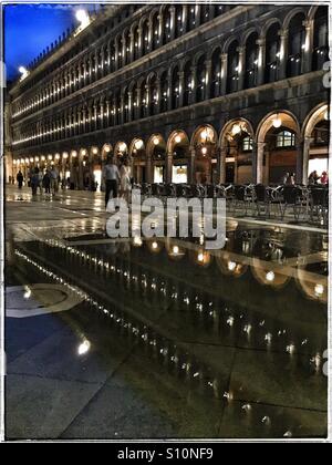 Un paio di passeggiare attraverso Piazza San Marco, Venezia di notte dopo la pioggia. Foto Stock