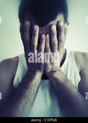 L'uomo nasconde il viso con le mani Foto Stock