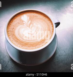 Un overhead di close-up shot di un fresco latte bevanda di caffè su un tavolo in metallo la superficie superiore. Una semplice composizione pulita. Foto Stock