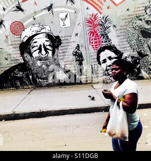 Un colombiano donna passa davanti ad un graffiti stencil artwork, creato da un artista chiamato Dj Lu, nel centro della città di Bogotá, Colombia, 13 marzo, 2016. Foto Stock