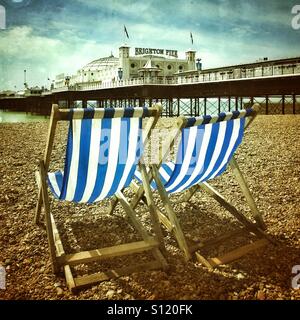 Blu e bianca a strisce di sedie a sdraio sulla spiaggia di Brighton Foto Stock