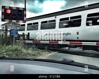 Abellio maggiore Anglian treni passeggeri da Ipswich a Lowestoft passando al di sopra di un passaggio a livello a Melton, Suffolk, Regno Unito. Foto Stock