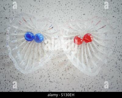 Due a forma di cuore piatti di cristallo contengono ciascuna due marmi. Foto Stock