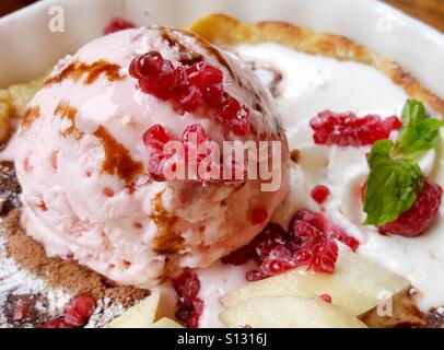 Dessert di gelato alla fragola su pancake con topping rasberry banana e salsa al cioccolato con foglie di menta piperita Foto Stock