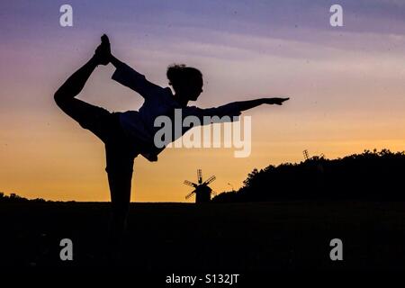 Silhouette di donna rendendo Natarajasana Yoga posa al tramonto Foto Stock