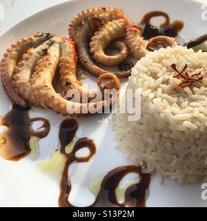 Polpo alla griglia con un lato di riso condito con zafferano Foto Stock