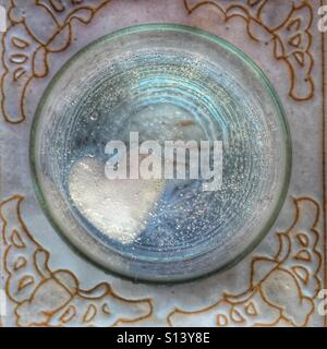 Vetro con una bevanda frizzante e di cuore a forma di cubo di ghiaccio, dal di sopra Foto Stock