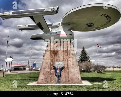 Un ragazzo è entusiasta di essere fotografato con un modello di Star Trek di starship Enterprise in Vulcan, Alberta, Canada. Foto Stock