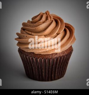 Un grande cupcake al cioccolato con glassa roteato isolato su un fondo bianco. Foto Stock